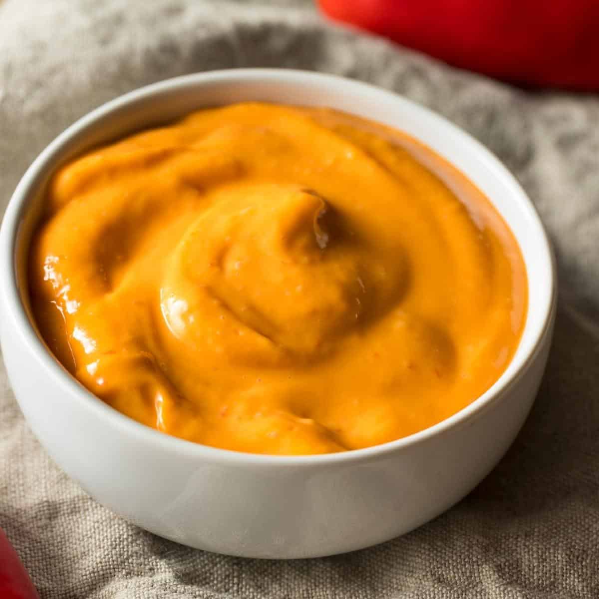 A orange sauce in a small white ceramic dish.