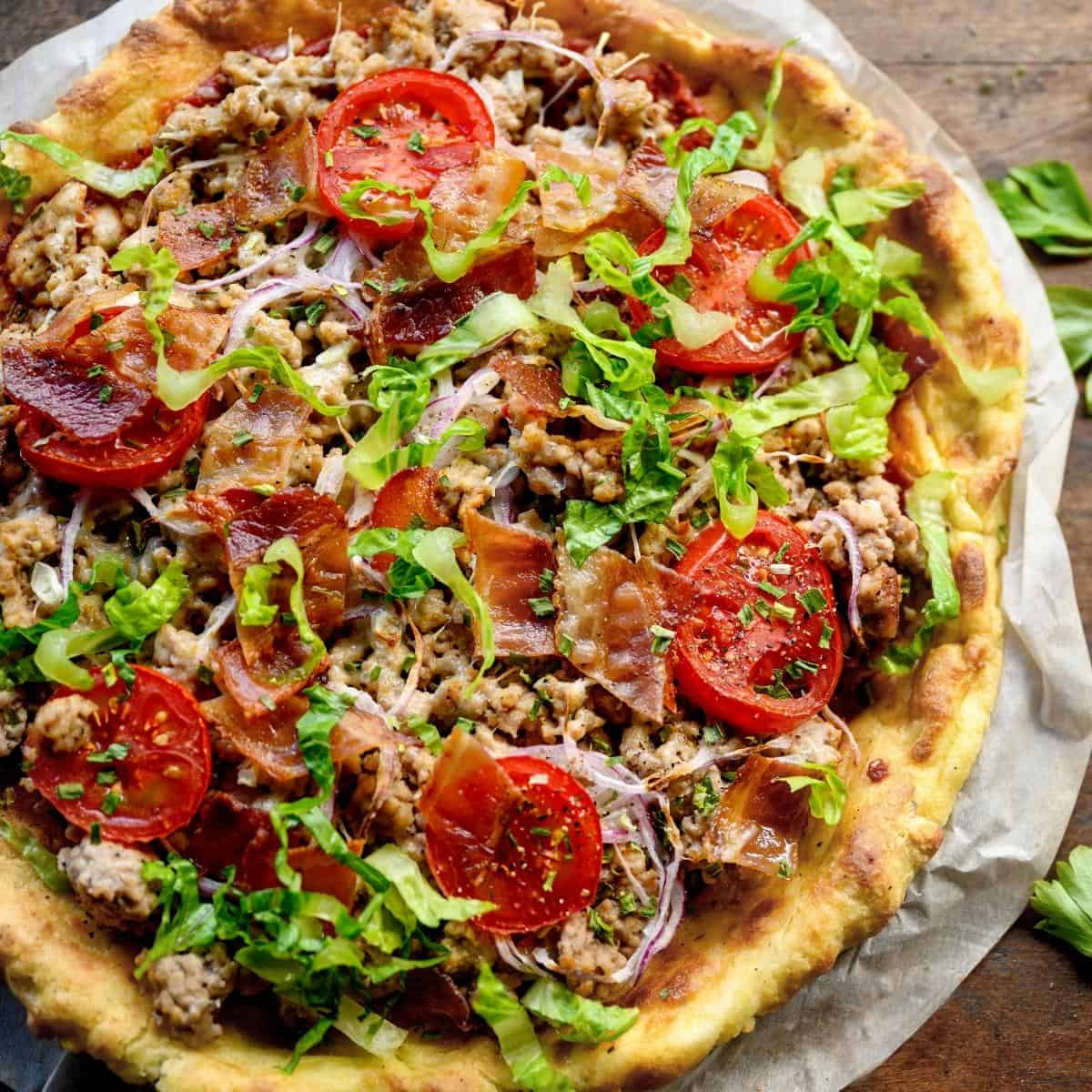 A lazy keto pizza topped with beef, bacon, tomatoes and lettuce.