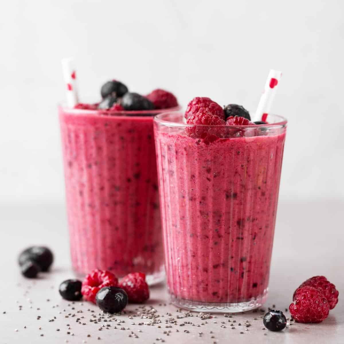 Two clear glasses filled with berry smoothies.