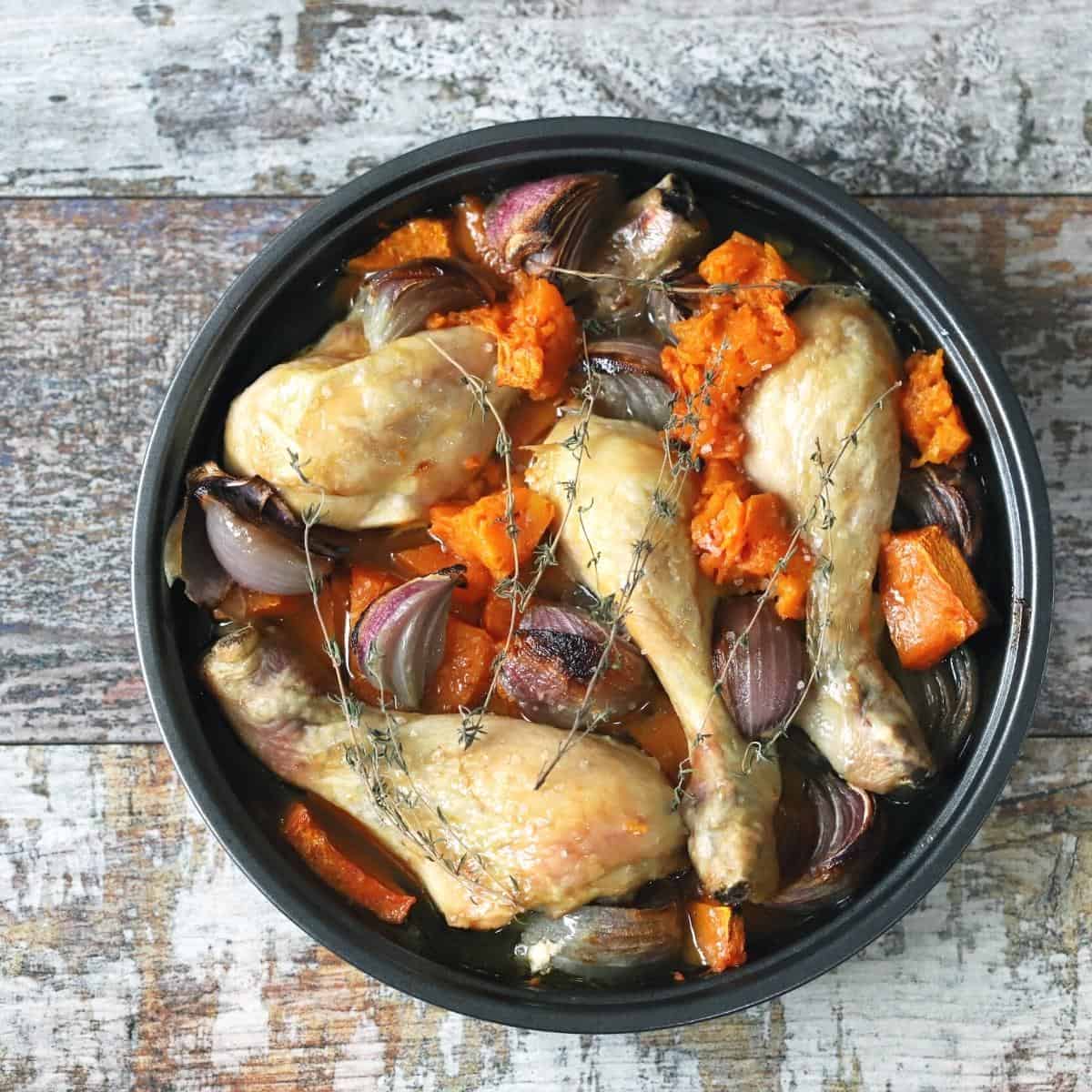 A crockpot slow cooker pot filled with chicken, veggies and herbs.