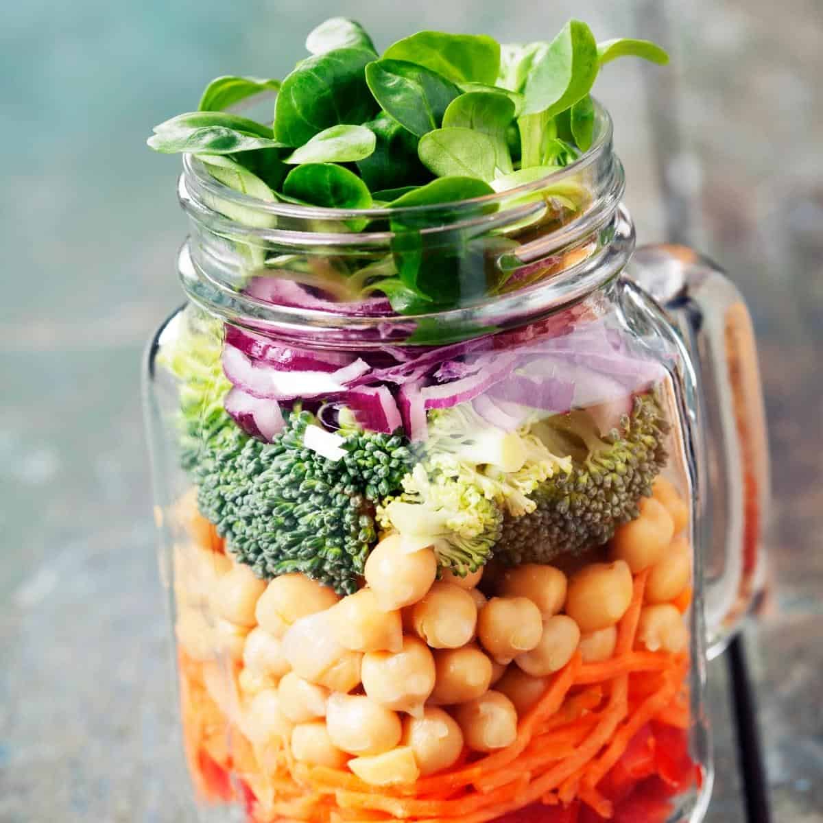 A vibrant multi-colored salad in a clear glass jar.