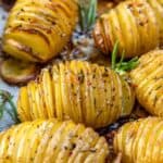 Sliced and seasoned hasselback potatoes with herbs ready to be served.