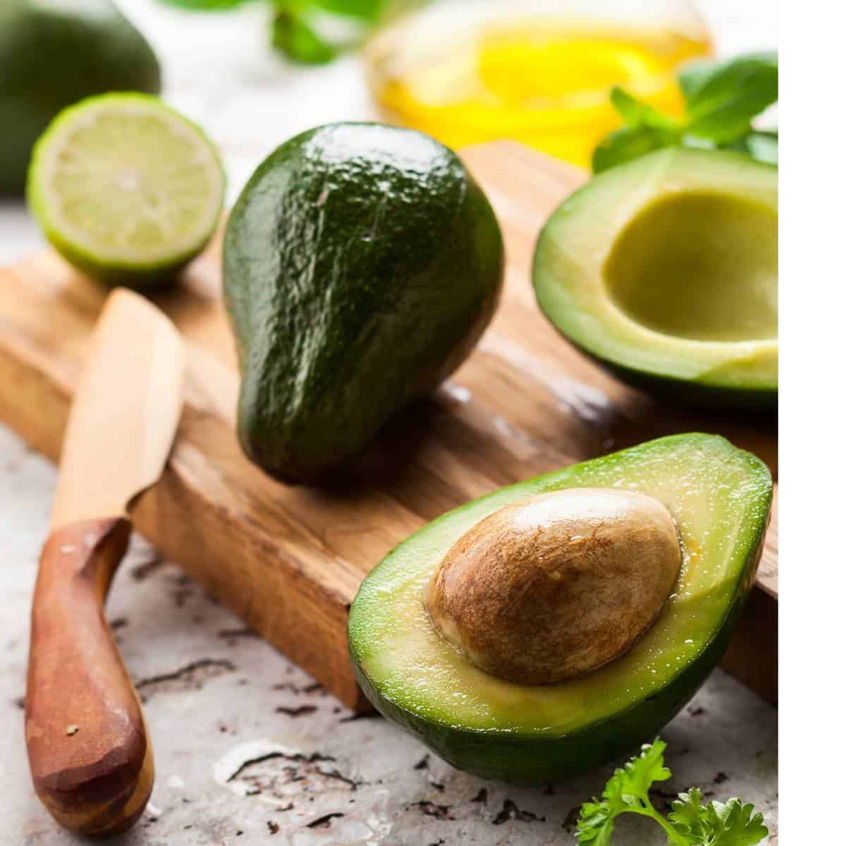 Fresh avocados (which you can freeze), lime, and olive oil on a kitchen counter.