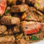 Close-up of air fryer steak bites seasoned with herbs, showing both seared exteriors and pink interiors.